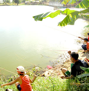 A man along with several kids go fishing on a small pond