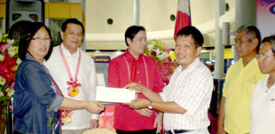 DOLE VI Director Aida Estabillo hands the check worth P217,380 to a representative of the municipality of Leganes as training assistance to farmer beneficiaries on organic fertilizer and vermiculture production under the DOLE’s Adjustment Measures Program during the Labor Day celebration in Iloilo City. Witnessing the event are Presidential Asst. for WV Raul Banias, Vice Mayor Jed Mabilog and farmer beneficiaries. (PIA)