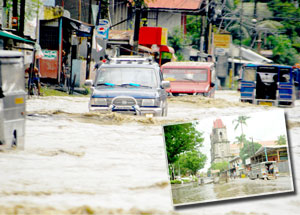 Vehicles negotiate the murky floodwaters covering Lopez Jaena Street in Jaro district