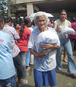 An old woman walks carrying with her relief goods. 