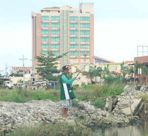 A man spends his time fishing on a pond in Barangay San Rafael, Mandurriao surrounded by commercial buildings.
