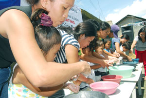 Parents teach their children proper hand washing in yesterday's first ever Global Hand Washing Day.