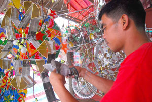 A man works on the lights of a parol which he sells along the road in Luna Street, La Paz. 