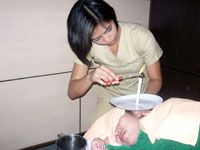 Earcandling process - inserting an aromatherapy candle into the ear.