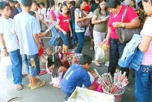 Children sell Christmas gift wrappers on a busy sidewalk in downtown Iloilo City so they could earn money for themselves and their family this holiday season.