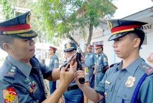 City police officer-in-charge Supt. Eugenio Espejo leads the removal of the tape from the firearms of policemen yesterday at the Iloilo City Police Office.