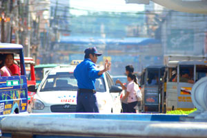 A traffic auxiliary directs traffic flow at the Arroyo Fountain rotonda in Iloilo City.