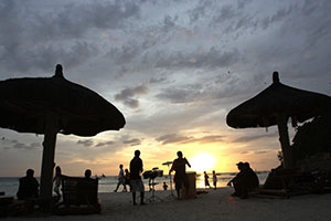 A typical sunset on Boracay Island with tourists strolling by the shore and resorts starting their entertainment presentation for their guests at night.