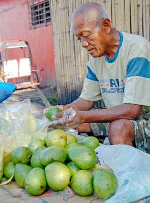 A vendor peels indian mangoes at Burgos Market in Bacolod City.