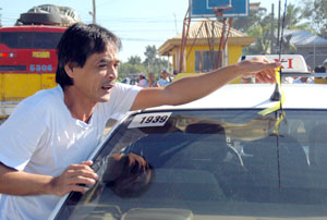 A taxi driver puts a yellow and black ribbon on the antenna of his taxi cab