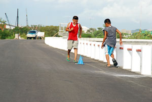 Two boys play with their own version of a wind-powered toy wagon