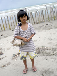 A little girl happily holds some coins from sale of boiled peanuts along Villa Beach.