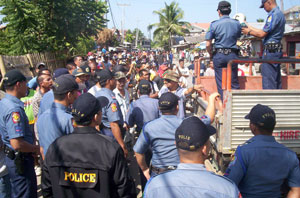 Policemen led by Roxas City police chief Leo Batiles watch over the railway squatters forming a human barricade