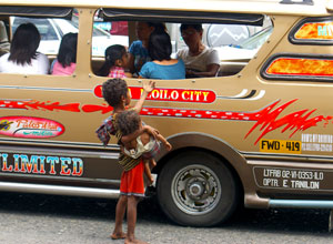 A young ati carries his younger sibling while begging from passengers of a jeepney along Valeria Street.