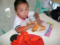 Three-year old  Joemarie Llamelo enjoys putting colors on his artwork.