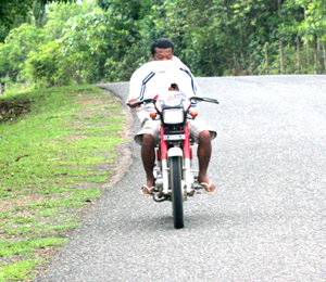 A man keeps on texting in his cellular phone while driving a motorcycle unmindful that he might incur an accident.