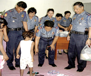 SLIPPERS FOR AETA KIDS. Personnel of the Iloilo Police Provincial Office led by Senior Supt. Renato Gumban (right) distribute slippers to 25 barefoot aeta kids