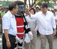 Provincial Administrator Raul Banias (right) raises a fist against the Aedes Aegypti mascot during the launching of the provincewide clean-up drive against dengue led by Gov. Arthur Defensor Sr. yesterday.
