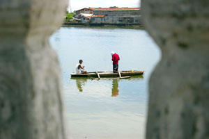 Two men cast their fishing net into the Iloilo River,